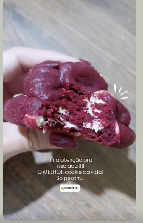 Story de cliente: mão segurando um cookie Ruby mordido, com o recheio de cream cheese à mostra